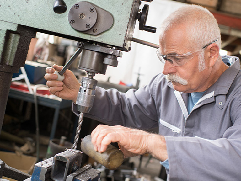 Ein älterer Mann an einer Industrie-Bohrmaschine